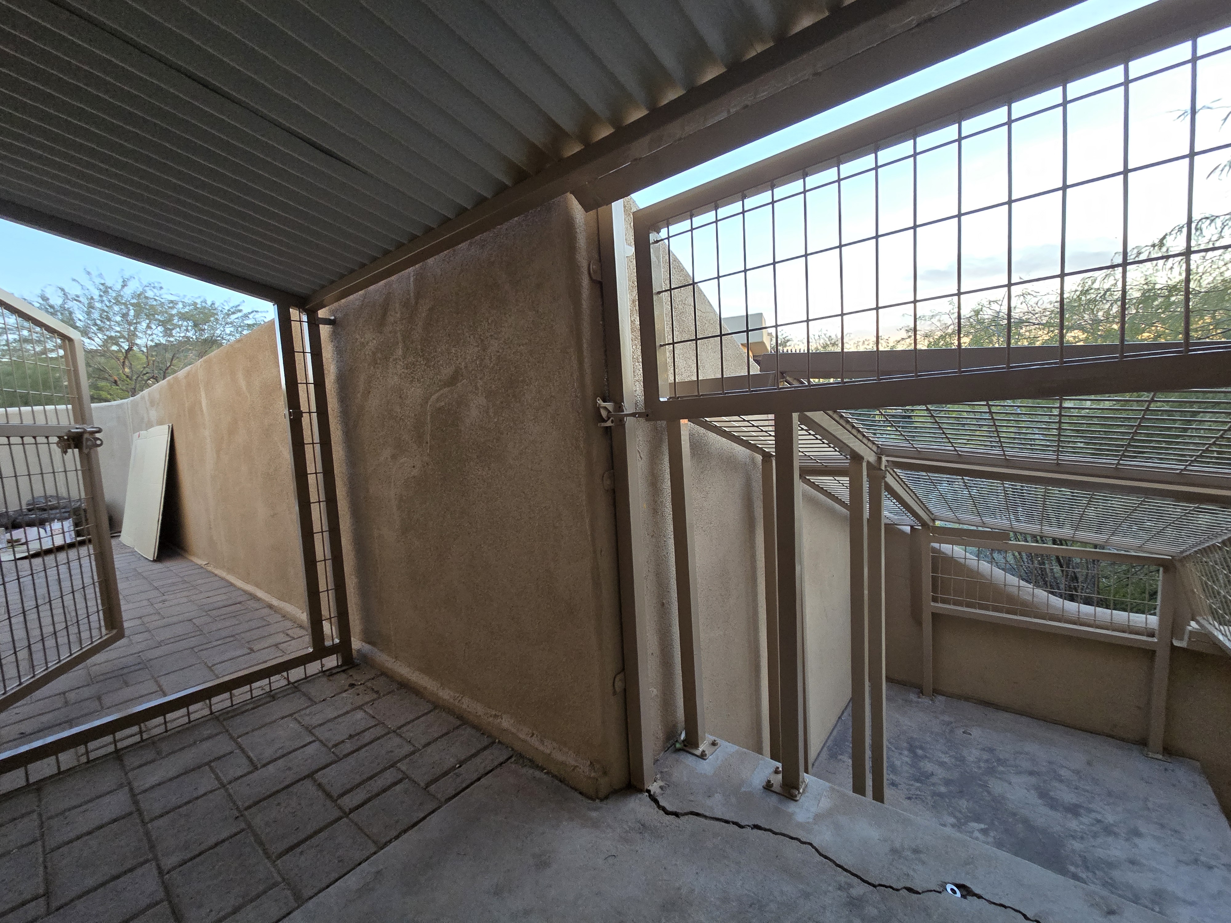 Covered patio section with corrugated roof and open gate